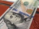 Купюра 100 долларов США в коричневом кожаном кошельке